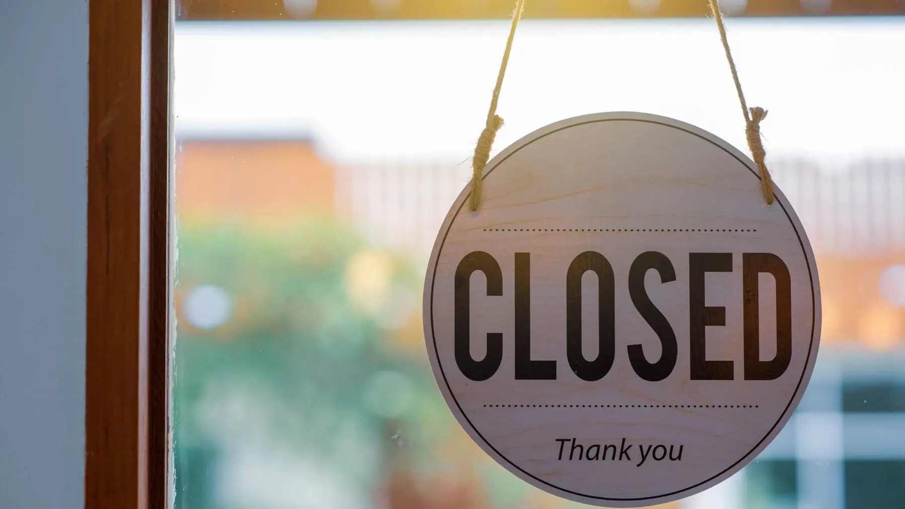 A round Closed sign hanging in the window of a shop door